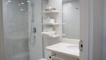 A modern bathroom with a glass-enclosed shower, a white sink, and a mirror.