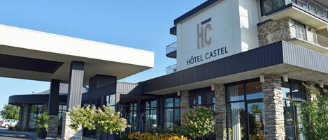 A modern hotel with a stone facade, large windows, and a balcony on the upper floor.