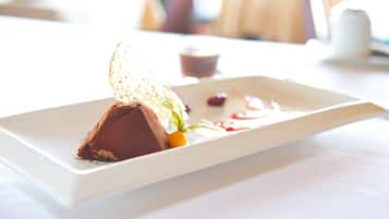 A dessert on a white rectangular plate with a small cup of tea in the background.