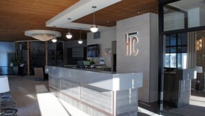 Un mostrador de recepción moderno con un logotipo, techo de madera e iluminación colgante.