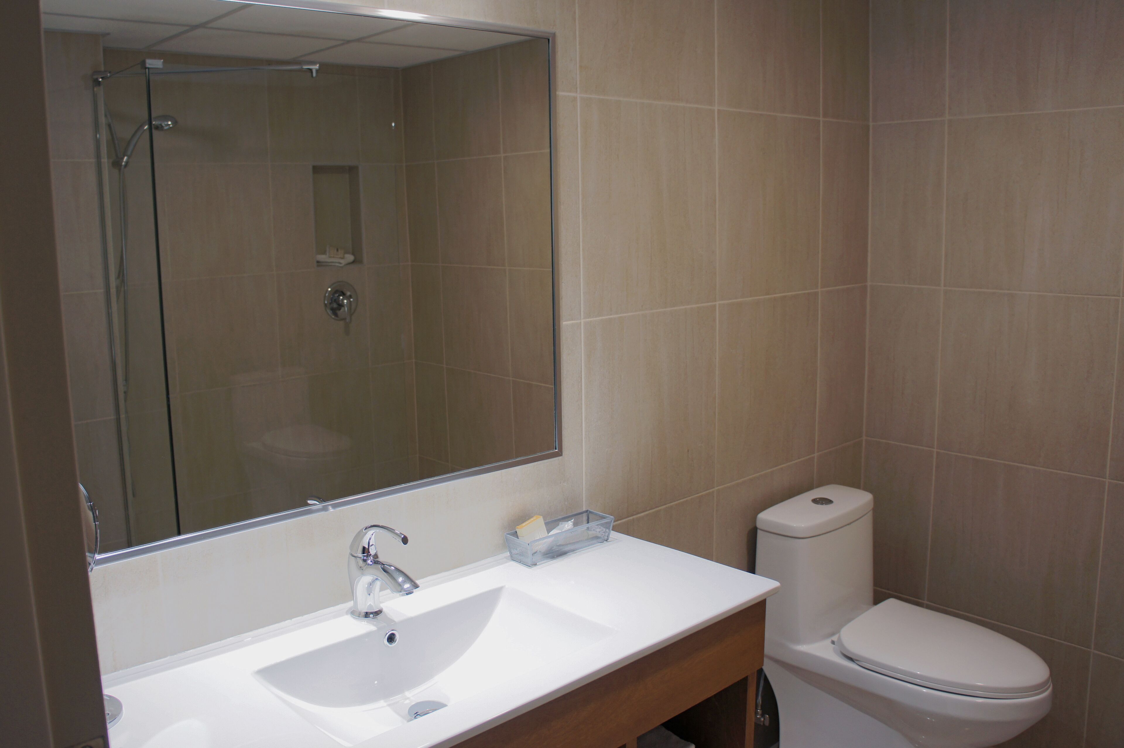 Un baño con lavamanos blanco, espejo, inodoro y ducha.