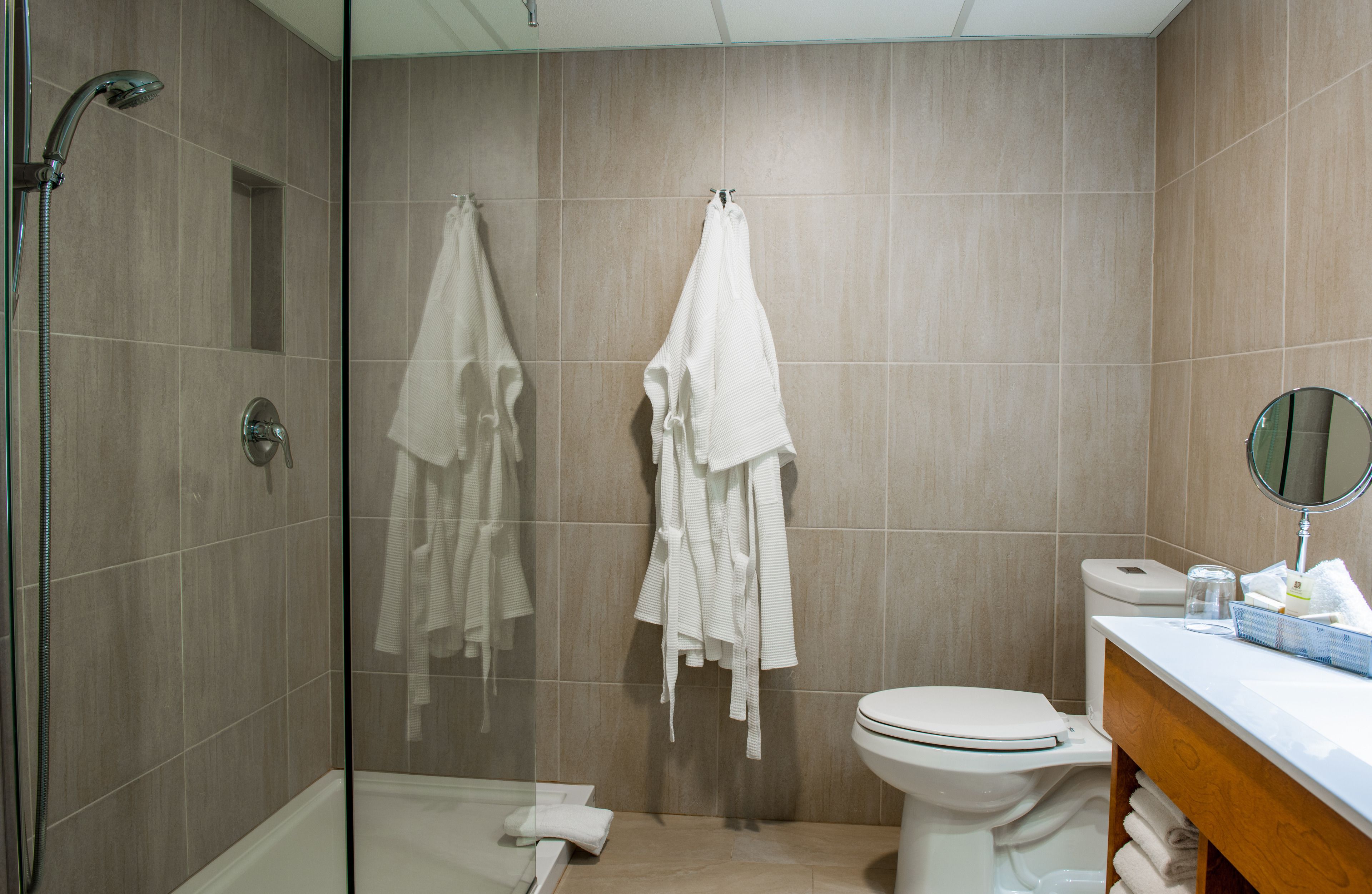 Une salle de bain moderne avec une douche à parois de verre, des toilettes et un meuble-lavabo avec un miroir.