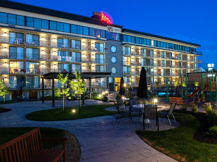 A hotel with multiple balconies, outdoor seating, and a pool area.