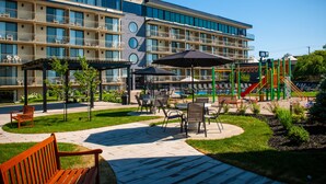 Un hotel con varios balcones, mobiliario exterior y un parque infantil.