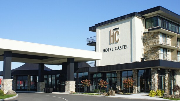 A modern hotel with a covered entrance, stone facade, and multiple balconies.