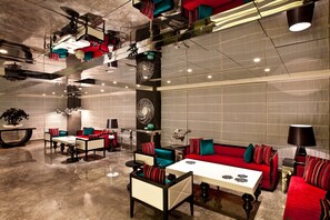 Un área de estar moderna con disposición de asientos, mesas y elementos decorativos.