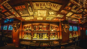 A bar with a curved counter, various liquor bottles, and a neon sign.