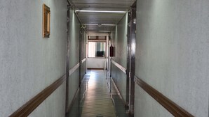 Pitkä, kapea käytävä, jossa on laatoitettu lattia ja puupanelointi seinissä.