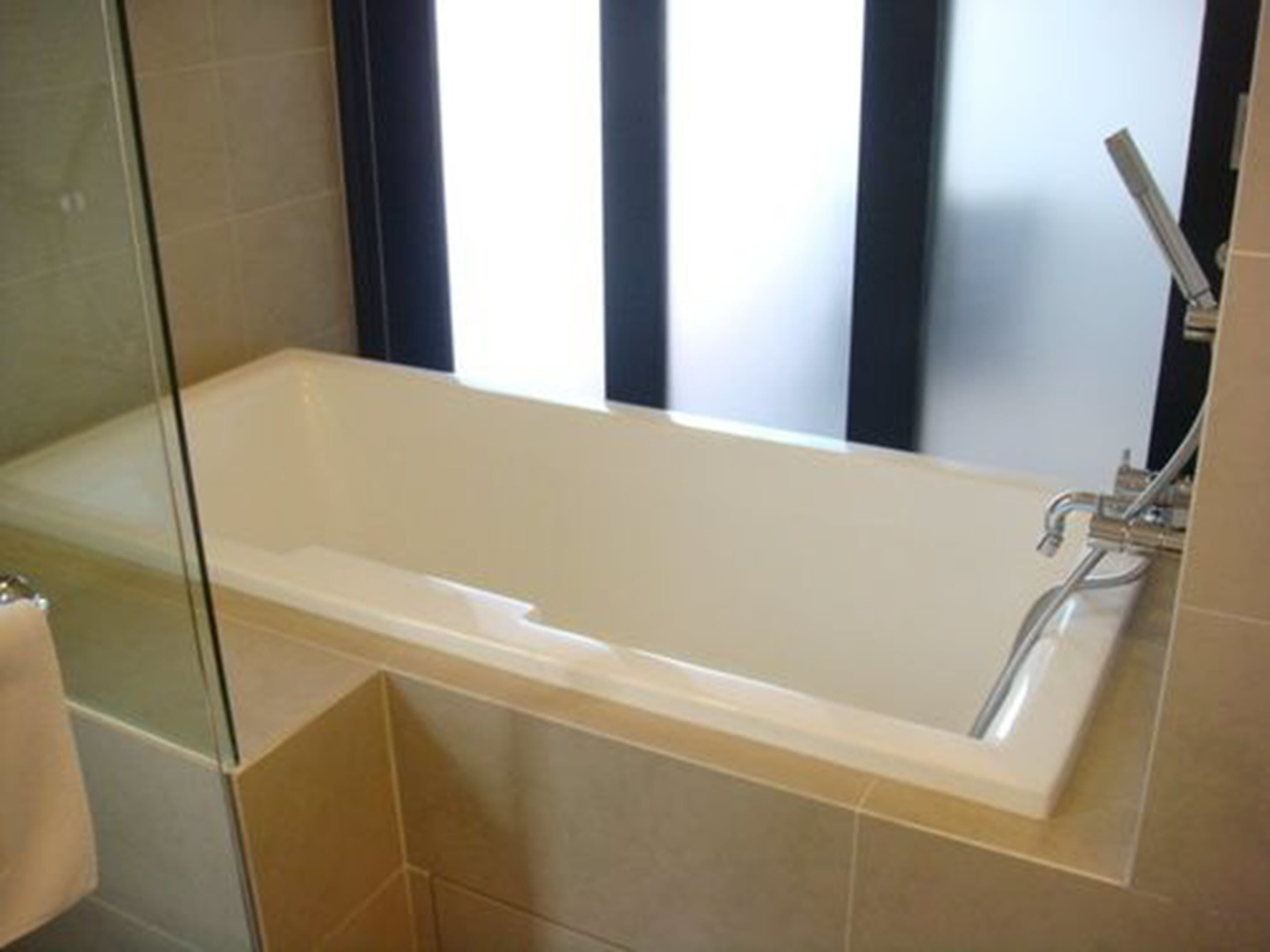 A modern bathroom with a freestanding bathtub, a glass shower enclosure, and a large window providing natural light.