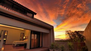 Un hotel moderno con balcón, ventanas amplias y vistas al atardecer.