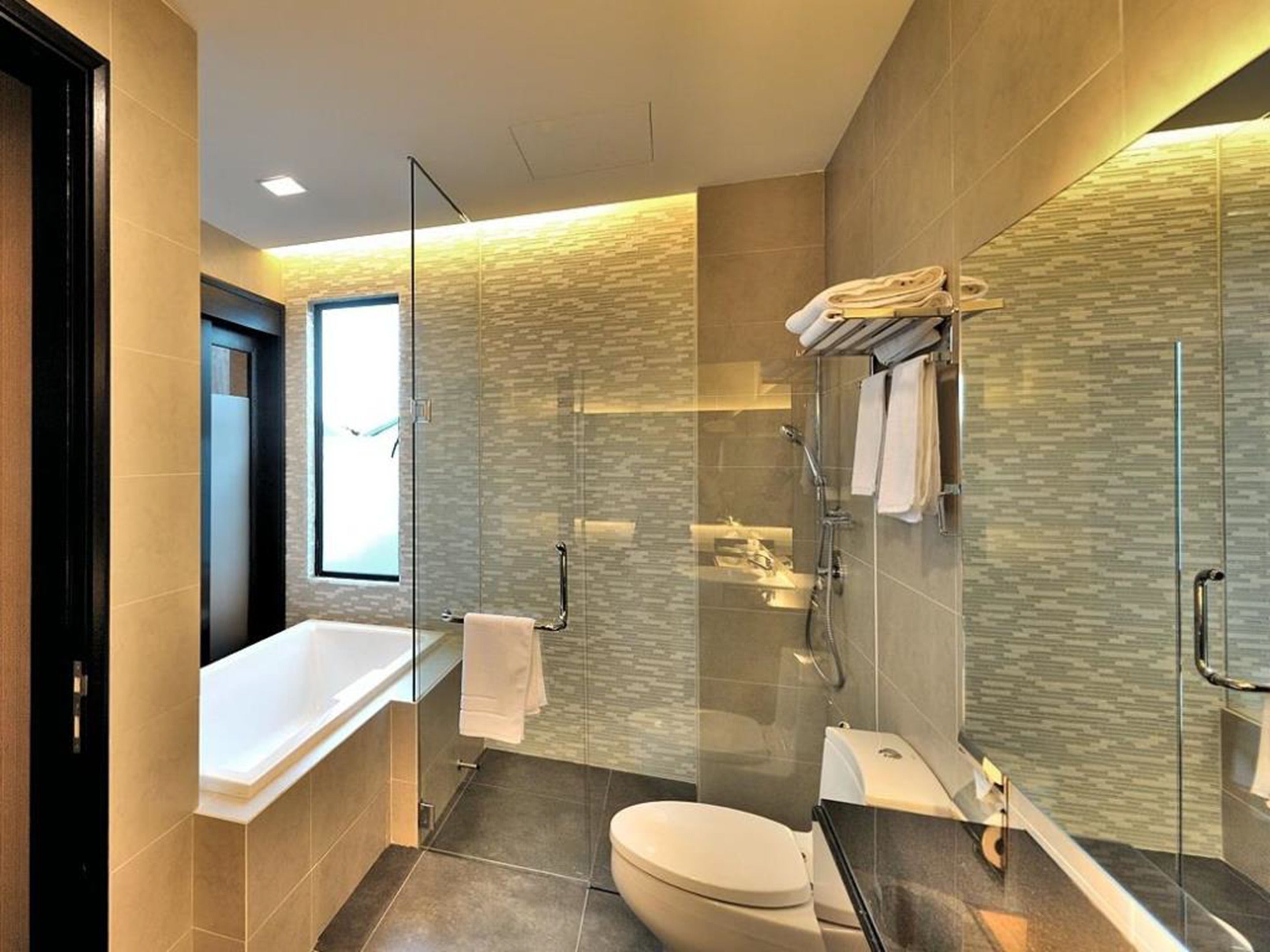Un baño moderno con ducha de vidrio, bañera y retrete.