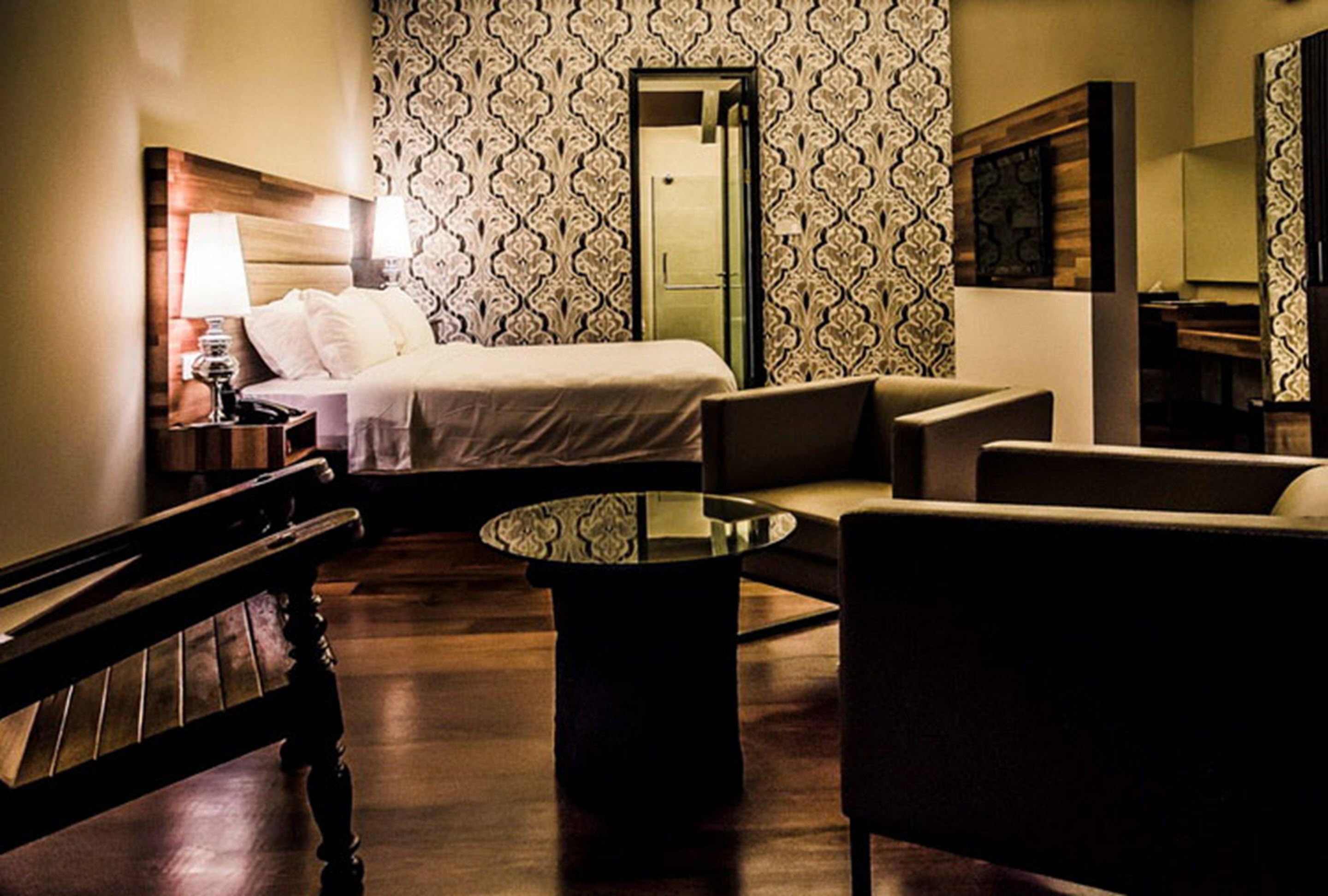 Una habitación de hotel con una cama, un sofá, una mesita de café y un banco.