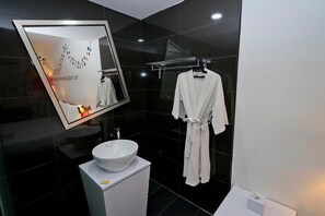 Une salle de bain moderne avec un grand miroir, un lavabo blanc et un porte-serviettes.
