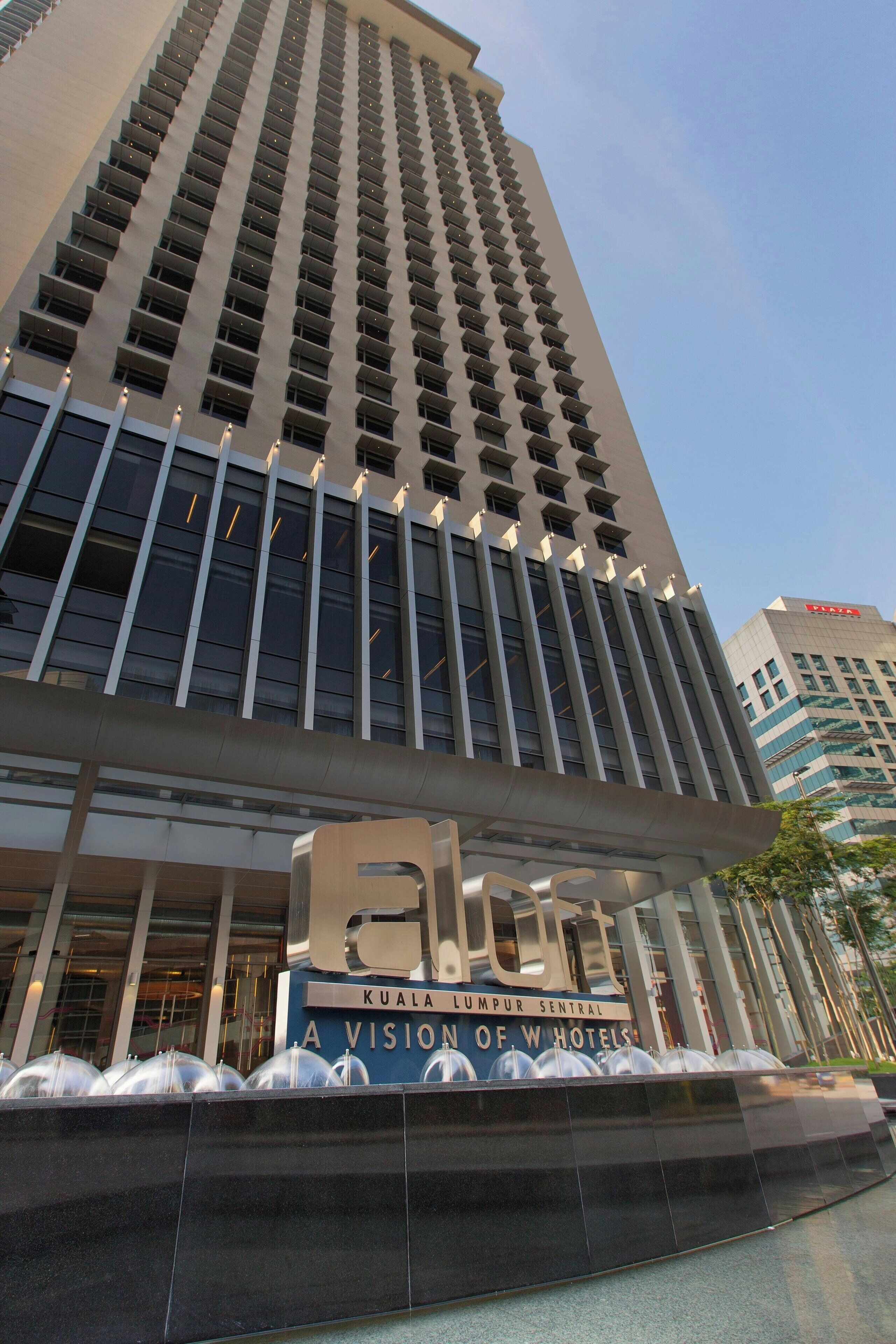 A tall hotel building with a modern design, featuring a prominent sign that reads "Elo" and "Kuala Lumpur Central A Vision of Hotels".