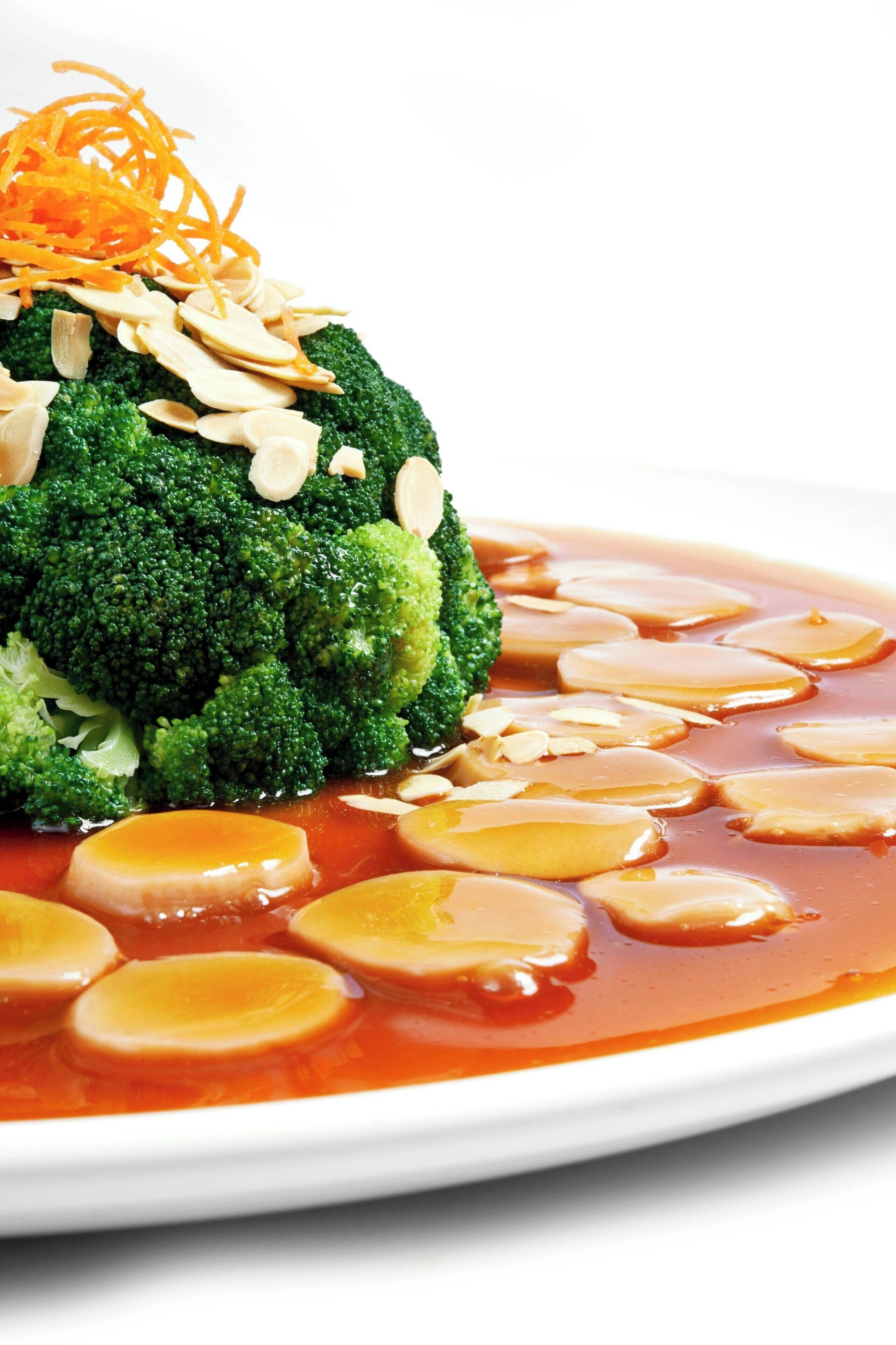 A dish with broccoli and sliced almonds on a white plate.