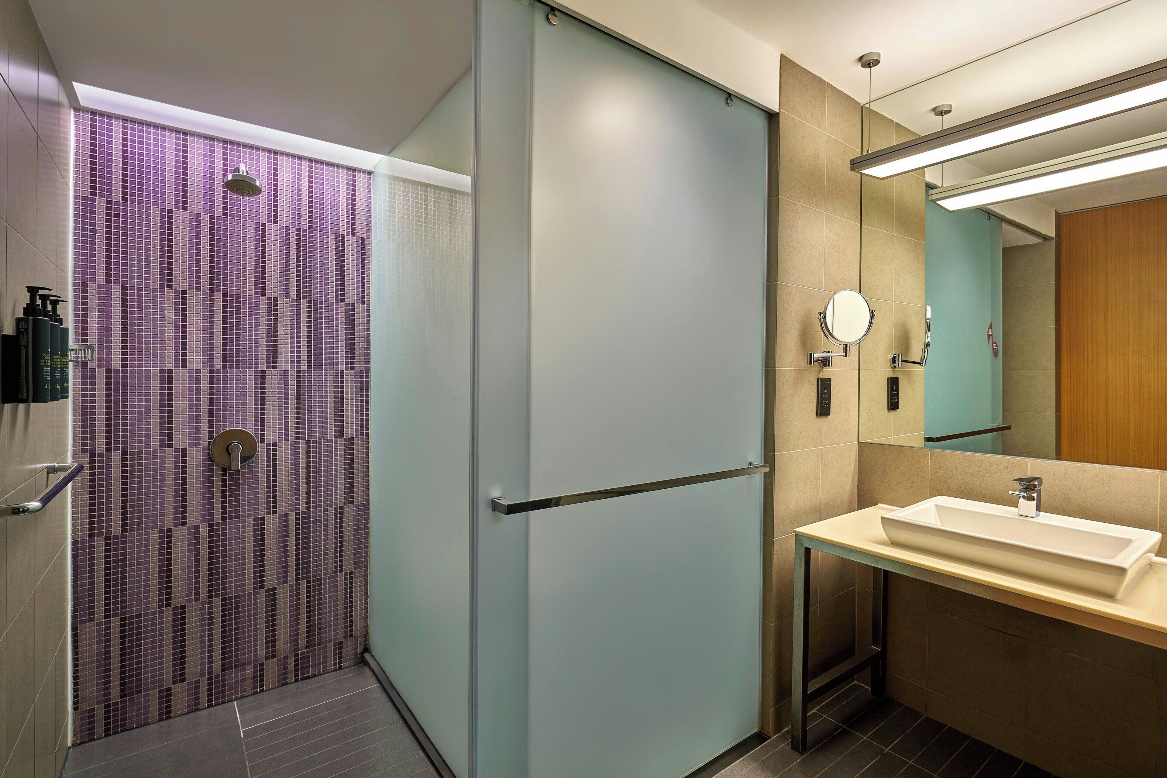 Un bagno moderno con cabina doccia in vetro, un lavabo con specchio e un porta asciugamani.