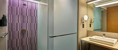 A modern bathroom with a glass shower enclosure, a sink with a mirror, and a towel rack.