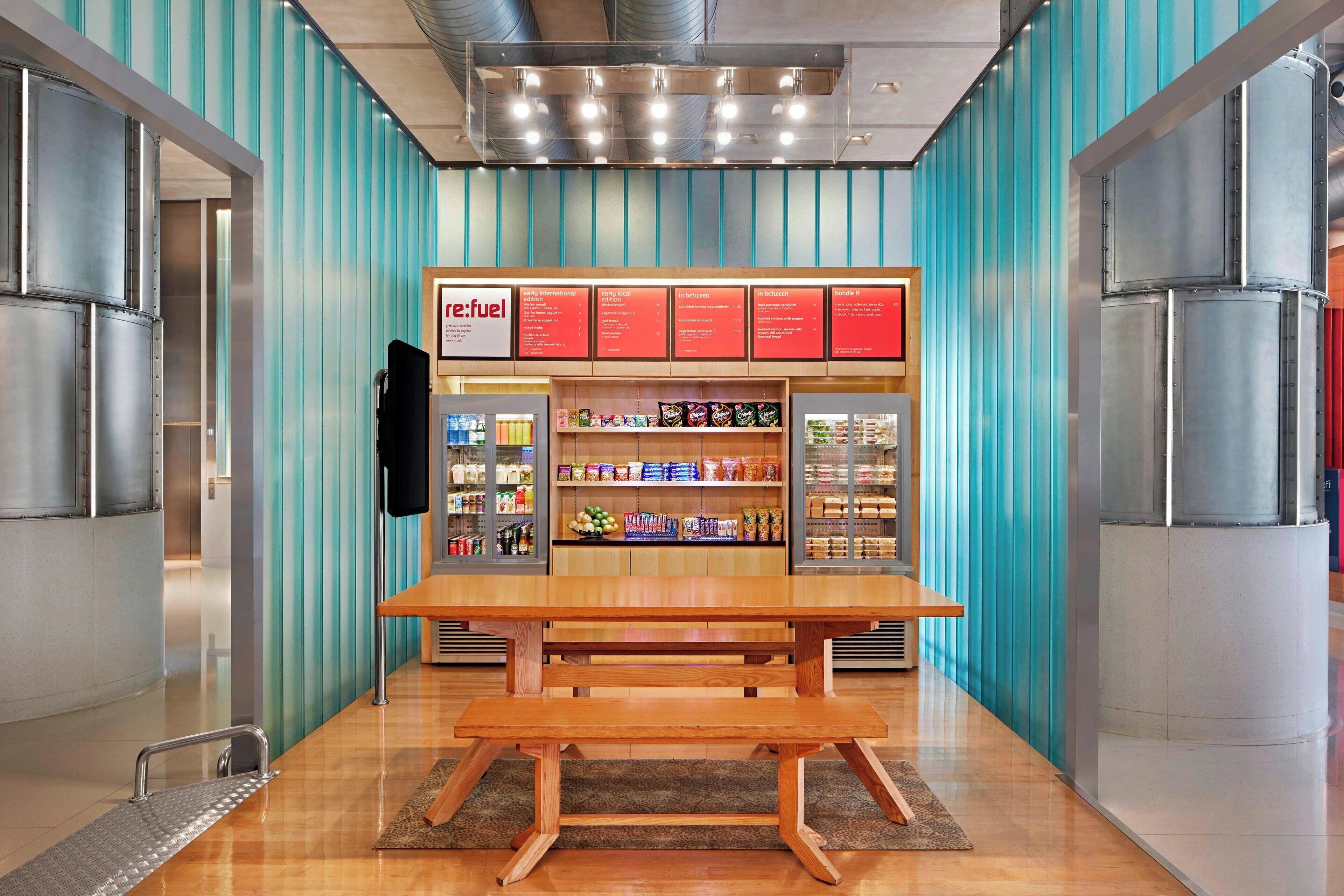 A food kiosk with a menu board, shelves of snacks, and a wooden bench.