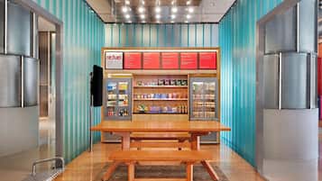 A food kiosk with a menu board, shelves of snacks, and a wooden bench.