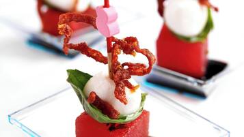 Una serie de platos de vidrio cuadrados con alimentos rojos y blancos, adornados con elementos rosados y marrones.