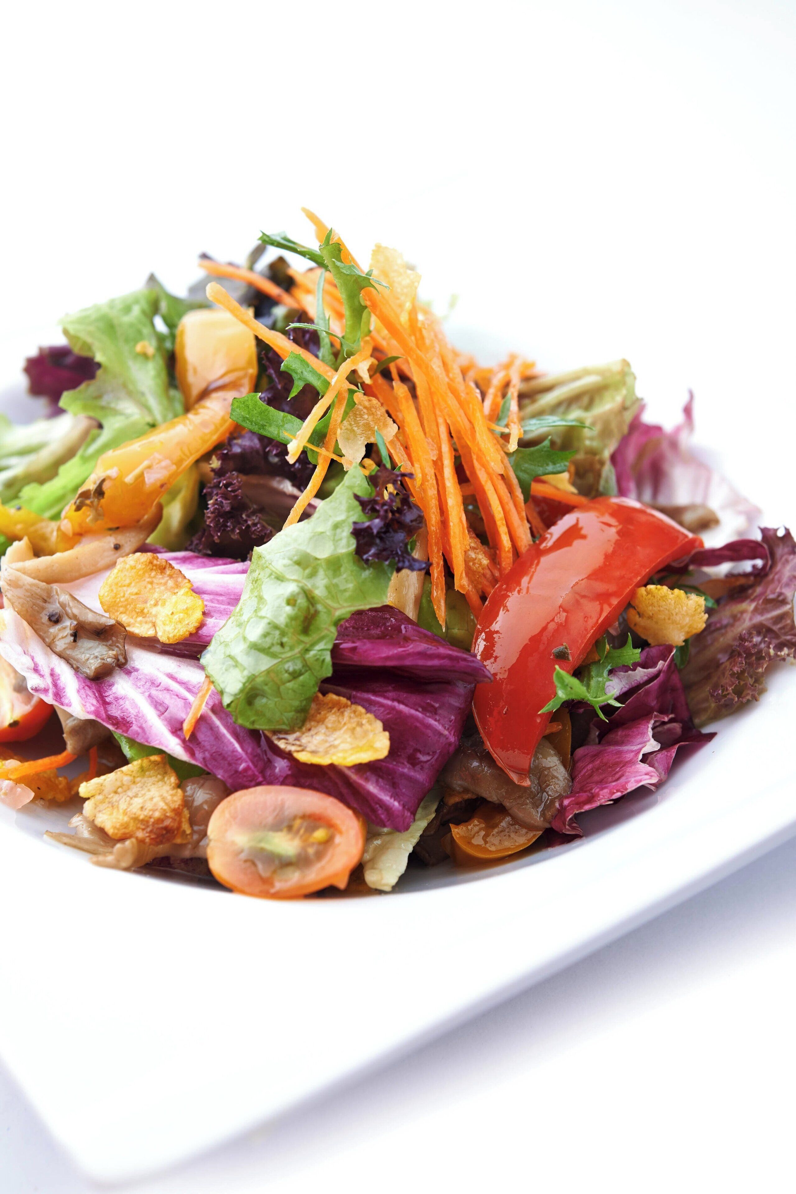 A plate of colorful salad with various vegetables and croutons.