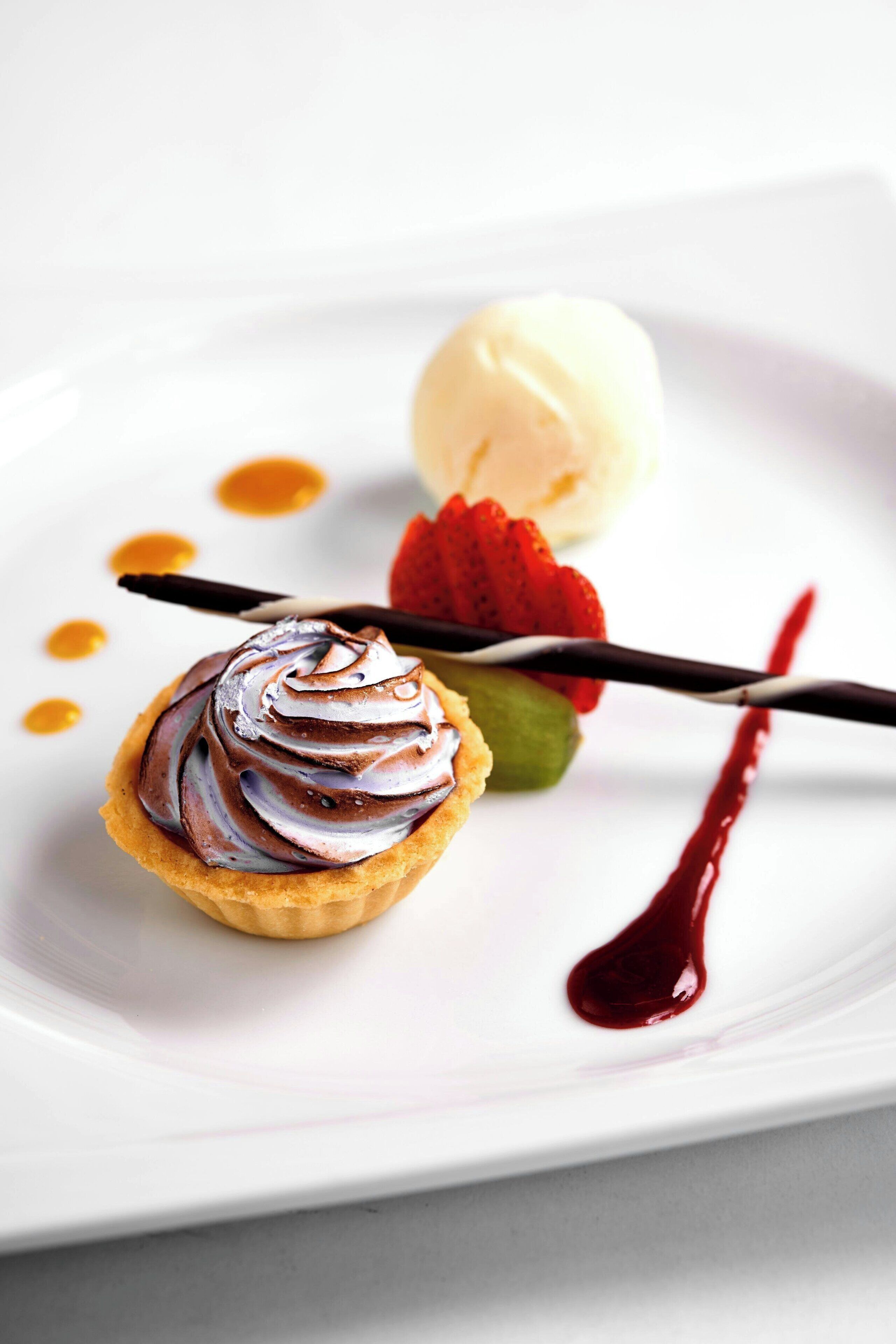 A dessert plate with a tart, ice cream, and a chocolate sauce.