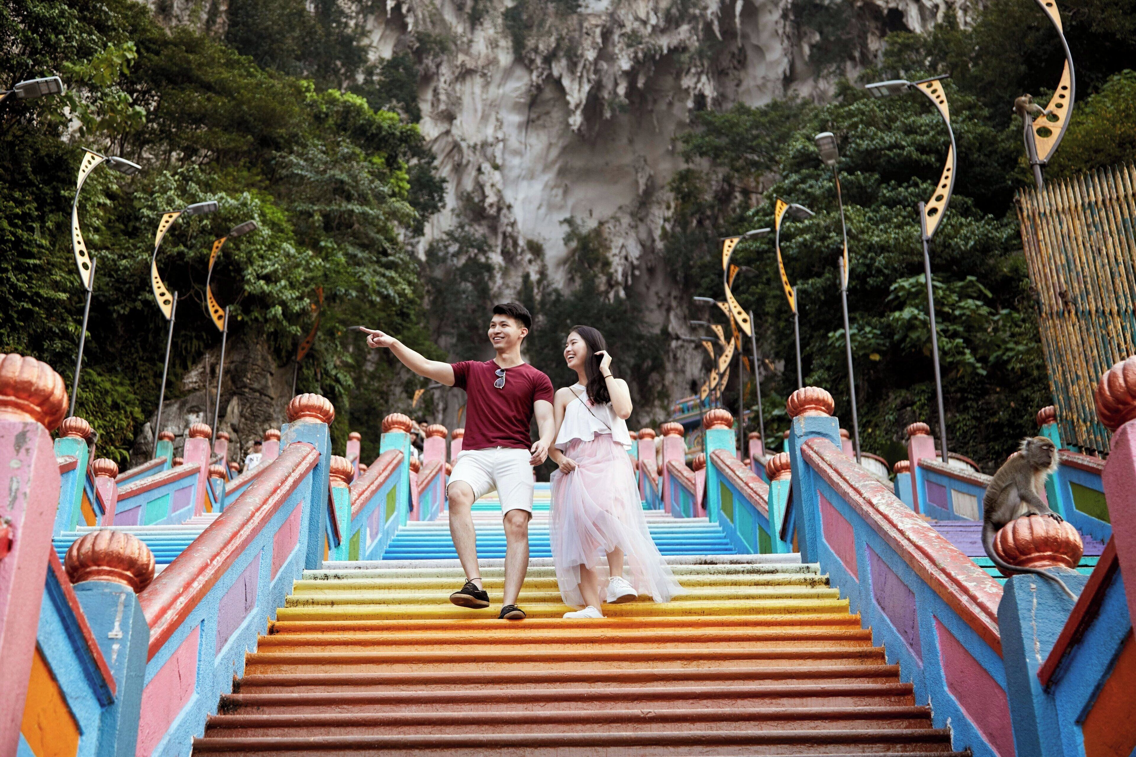 A couple on a colorful staircase with a monkey on the railing.