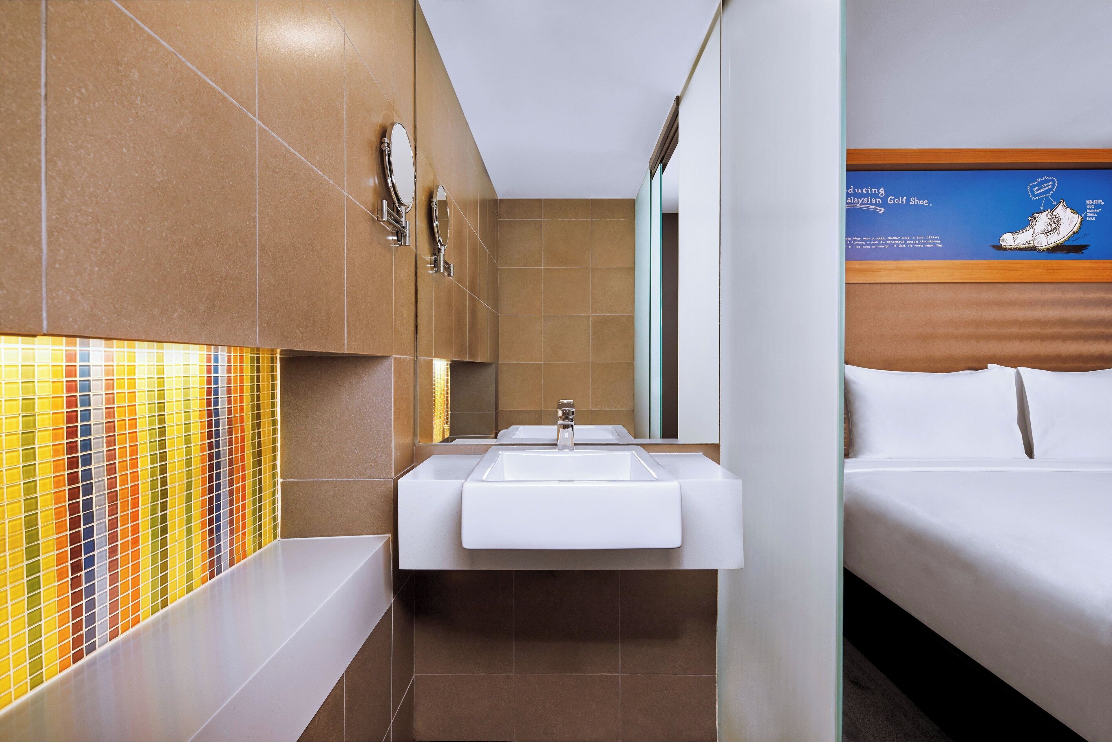 Un baño moderno con un lavamanos blanco, un espejo y una pared con mosaicos de colores.
