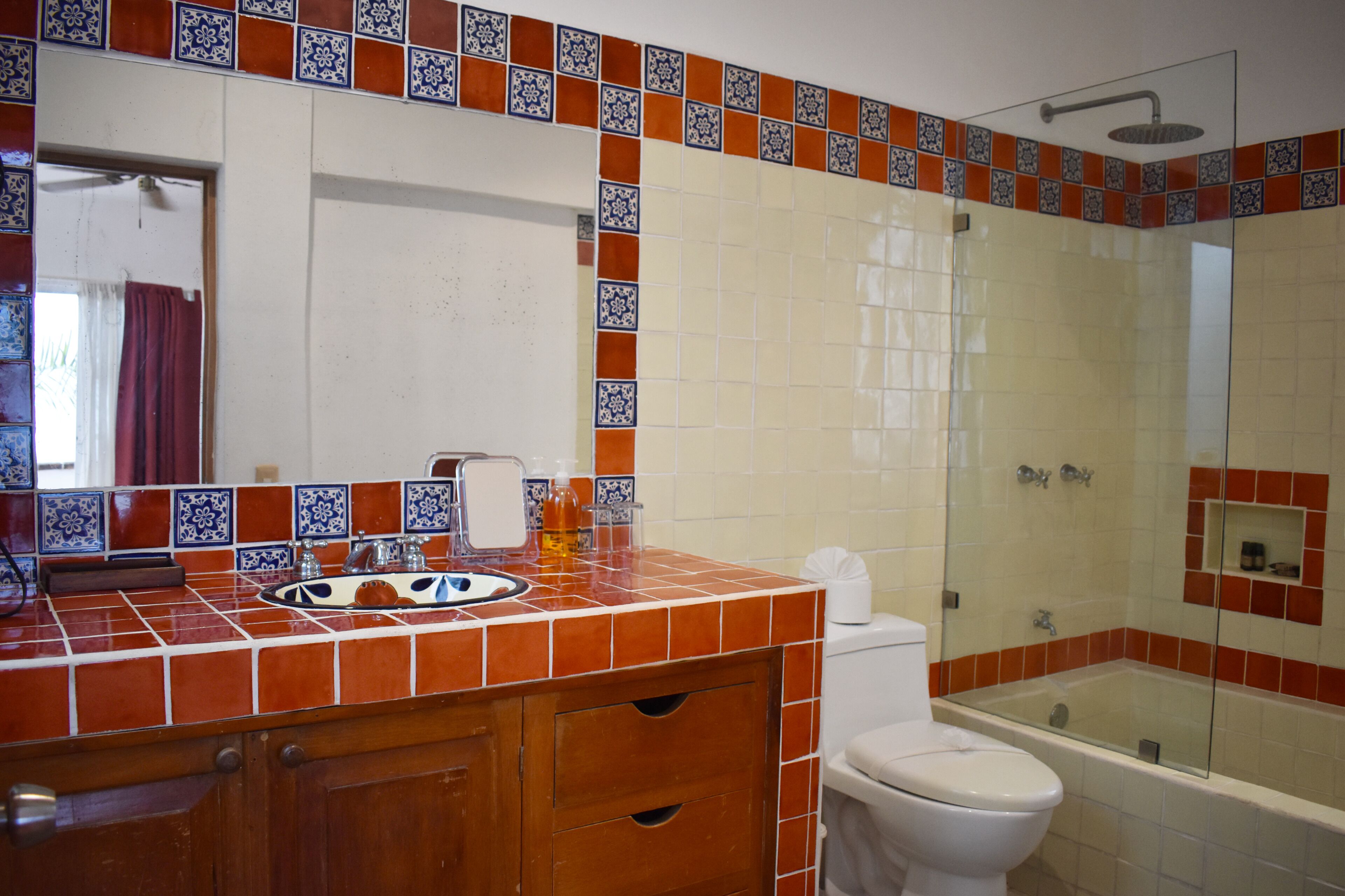 A bathroom with a tiled shower, a toilet, and a sink with a mirror.