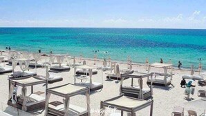 A beach with multiple sunbeds arranged in rows. - Mar Azul Suites 5ta Av (Playa del Carmen)