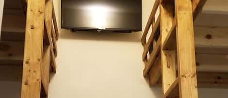 A bunk bed room with a flat-screen TV mounted on the wall.