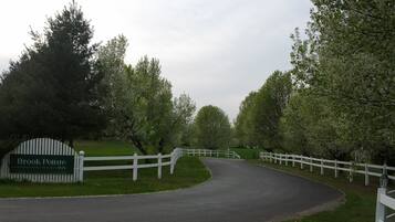 Une route menant à l’auberge Brook Pointe, bordée d’une clôture blanche et d’arbres des deux côtés.