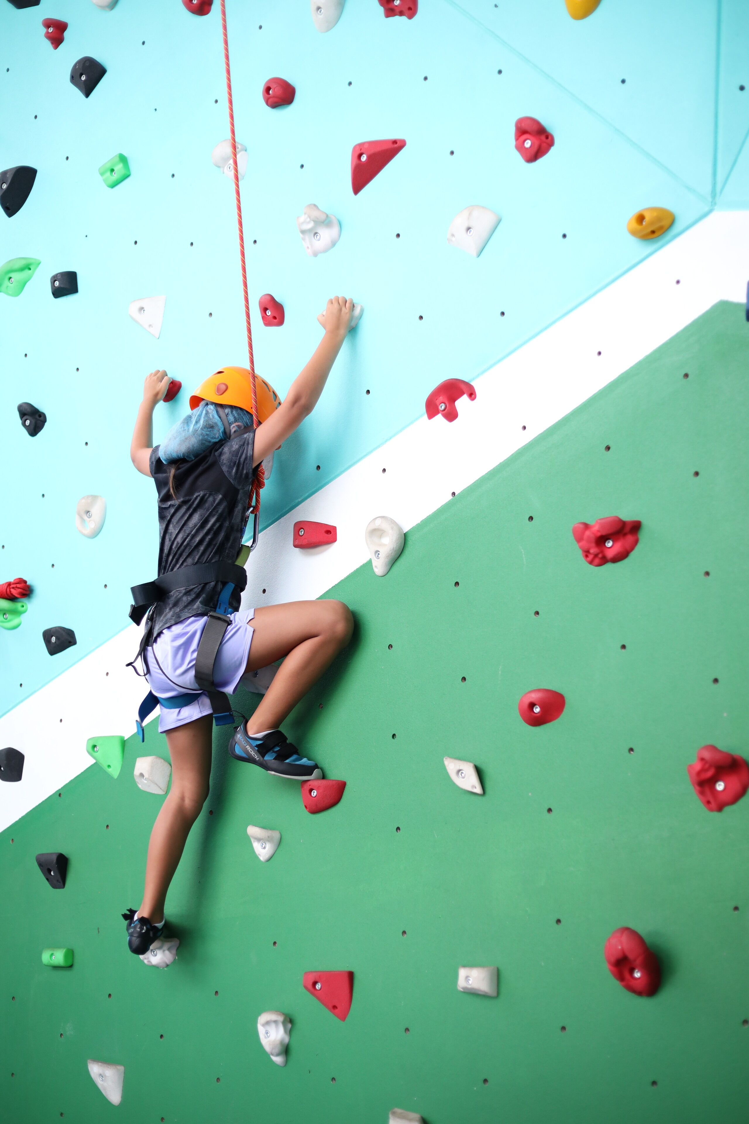 A person climbing a wall with various colored holds.