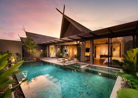 A modern house with a swimming pool, a covered outdoor seating area, and a well-lit interior.