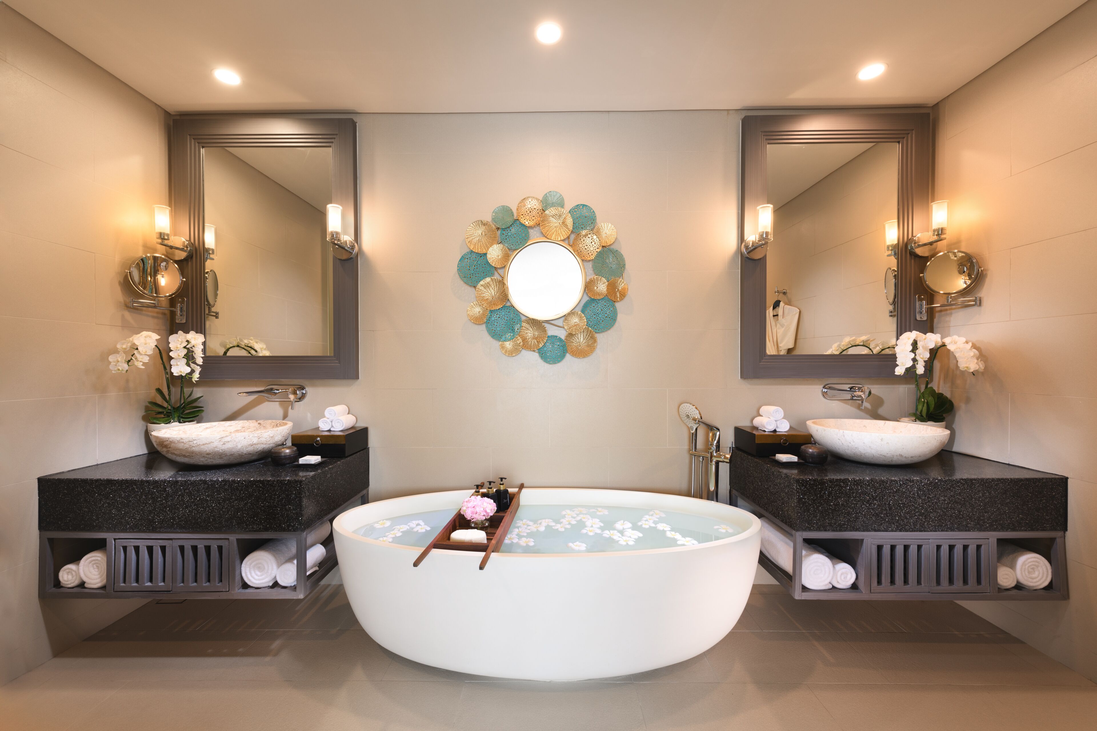 Un baño moderno con una bañera independiente, dos espejos grandes y un adorno de pared.