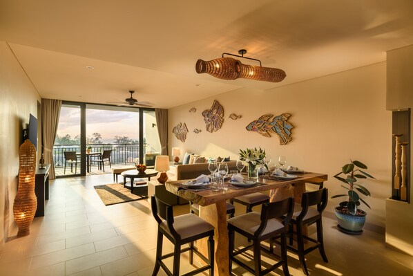 A dining area with a wooden table set for four, surrounded by chairs, with a view to the outside.