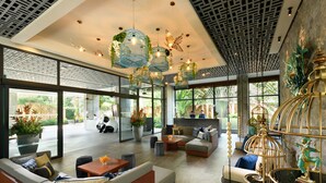 Eine geräumige Lobby mit moderner Sitzgelegenheiten, großen Fenstern und dekorativen Vogelkäfigen.