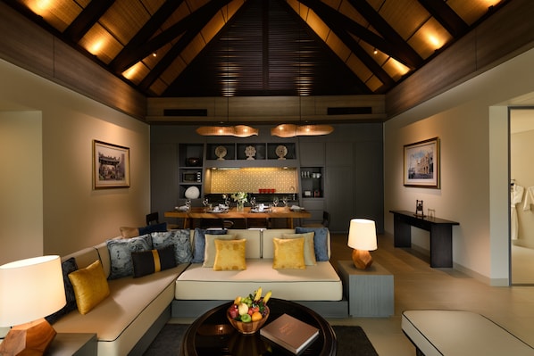 Una sala moderna con sofá, mesa de centro y comedor, con una cocina al fondo.