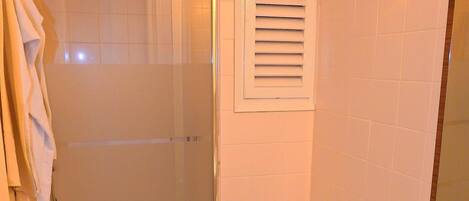 A bathroom with a glass-enclosed shower, a toilet, and a sink with a mirror.