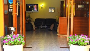 Entrada d'hotel amb un sòl de rajoles, un sofà i una televisió penjada a la paret.