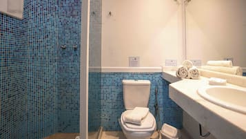Un baño con inodoro, lavamanos y cabina de ducha.