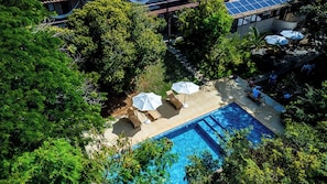 An aerial view of a hotel with a swimming pool surrounded by lush greenery and outdoor seating. - Vila Pitanga (Búzios)