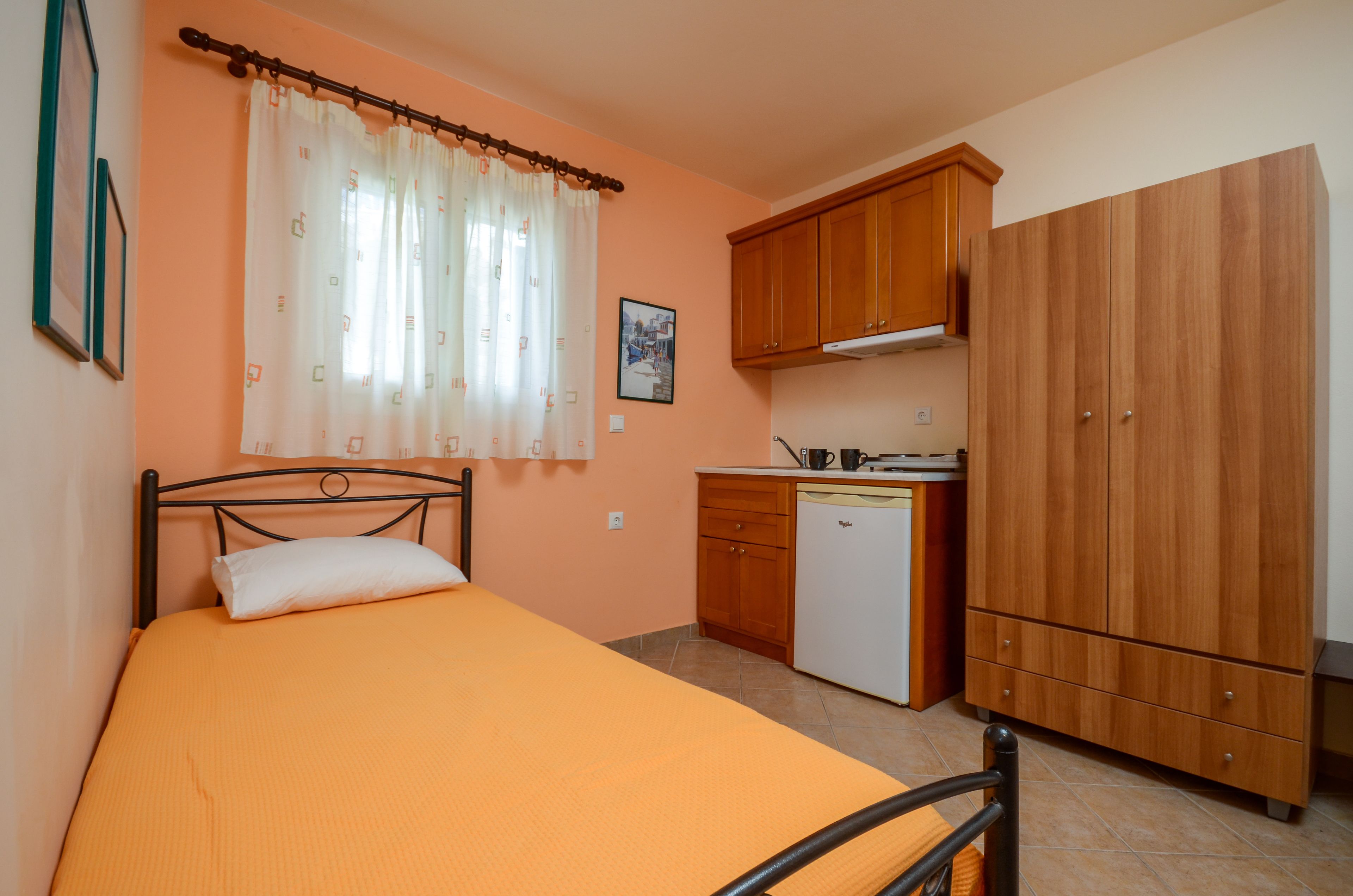 Un dormitorio con cama, una pequeña kitchenette y un armario.