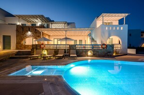 Un hotel moderno con piscina, mobiliario exterior y un arco de piedra.