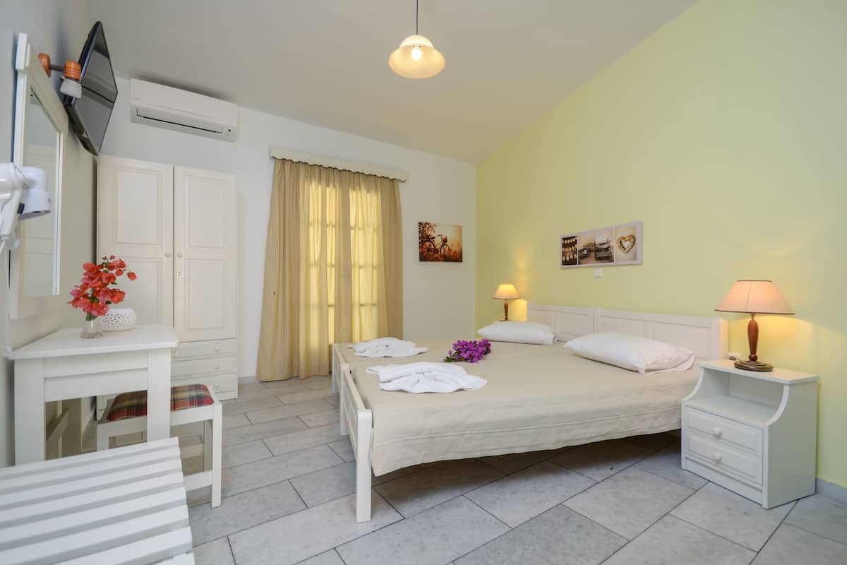 A hotel room with a bed, bedside tables, a desk, a chair, and a mirror.