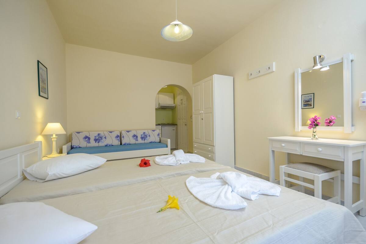 A hotel room with two beds, a white vanity with a mirror, and a small desk.