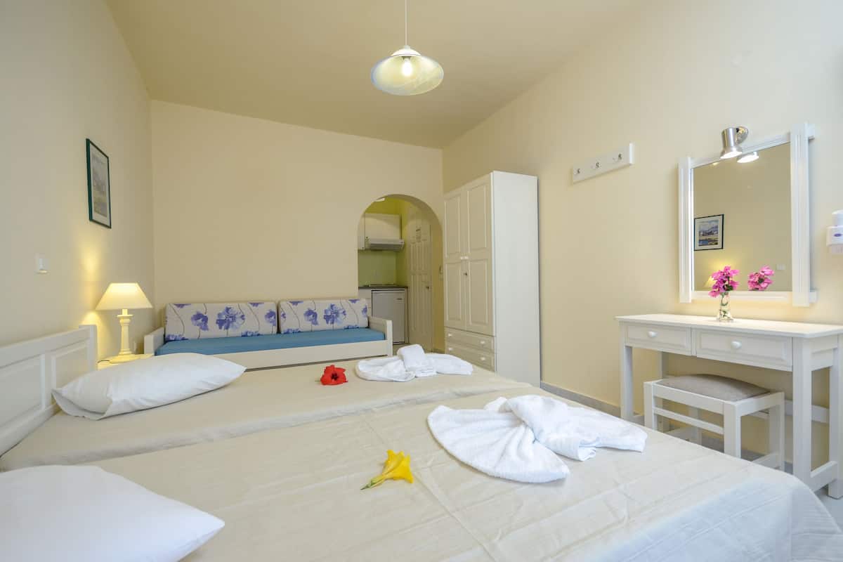 Quarto de hotel com duas camas, uma toucador branca com espelho e uma pequena mesa.