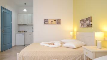 A bedroom with a bed, bedside tables, and a small kitchenette.