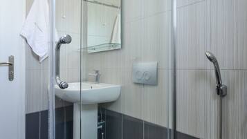 A modern bathroom with a glass-enclosed shower, a white toilet, a sink, and a mirror.