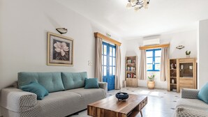 A living room with a sofa, coffee table, and a bookshelf. - Hotel Francesca (Naxos)